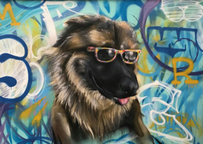 Oeuvre faite à la bombe sur mur d'un chien à lunettes sur un fond graphique avec des lettrages